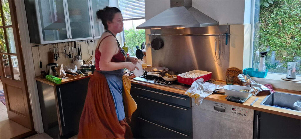 noor beweegt in de keuken en kijkt overwegend naar haar werk - een heleboel pannen met eten